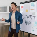 Pengusaha muda mempresentasikan pitch deck bisnis dengan grafik dan diagram di papan tulis kepada tim